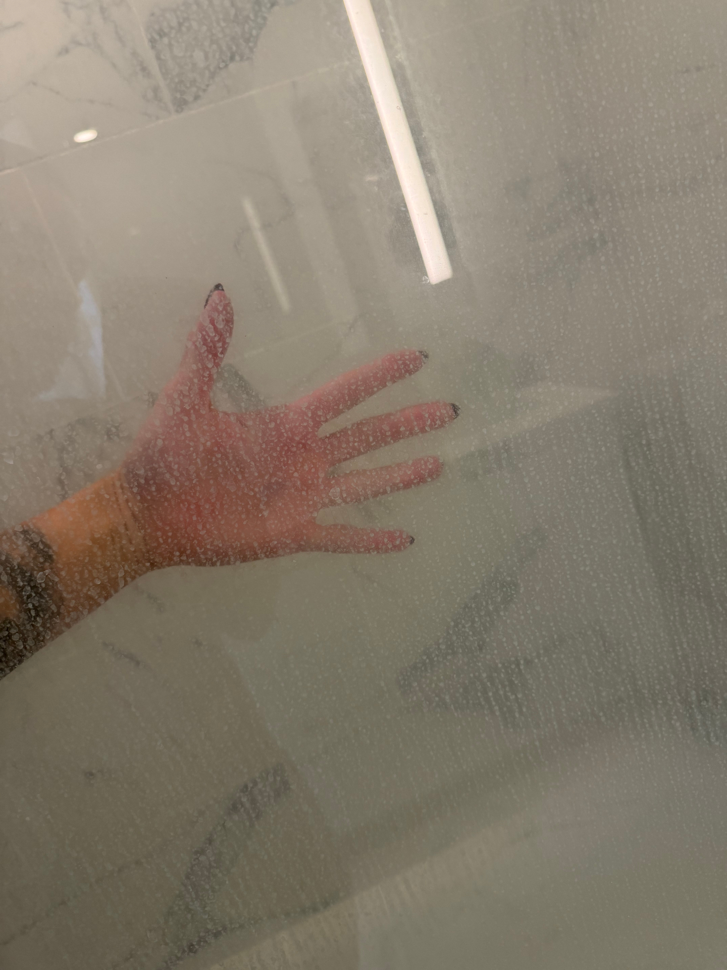 Cloudy shower glass covered in mineral spots before cleaning