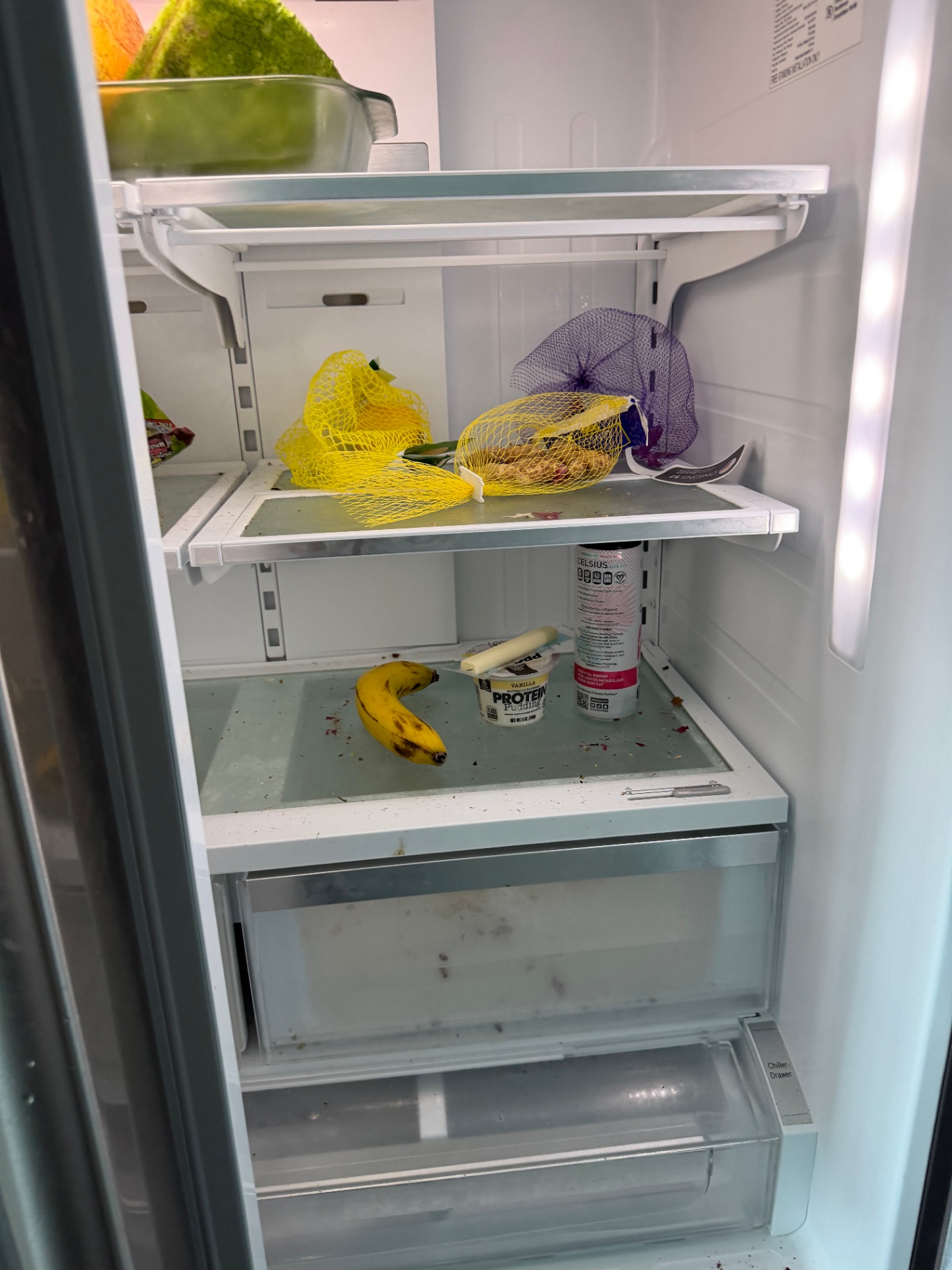 Refrigerator interior with crumbs and spills before cleaning